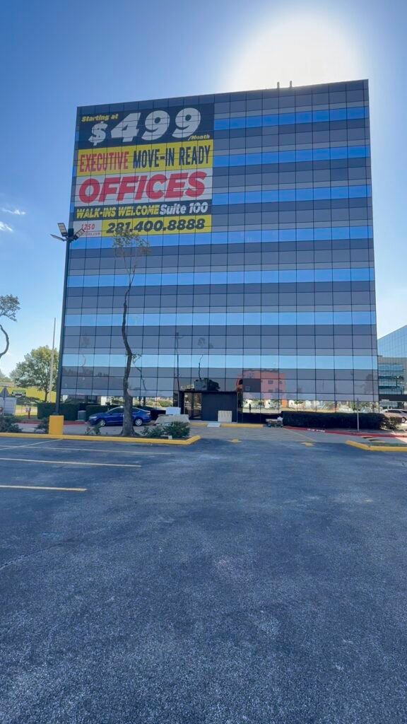 Large window banner advertising move-in ready offices on a Houston office building
